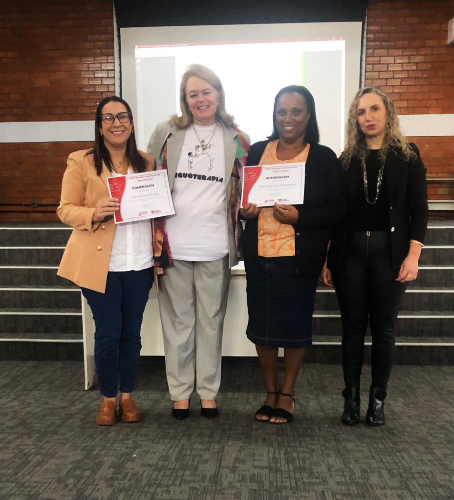 4 pessoas em pé, ambiente interno, posando pra foto e segurando diploma