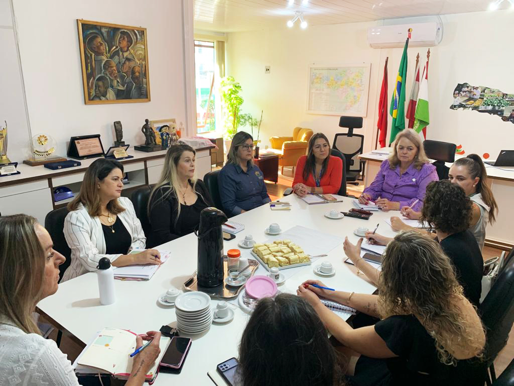 Ambiente interno, sala de reuniões, 8 pessoas sentadas