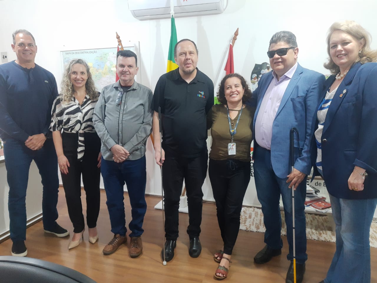 Na foto aparece sete pessoas em pé posando para foto. são quatro homens  e três mulheres. Eles fazem parte do Ministério dos Direitos Humanos e Cidadania, que vieram conhecer a estruturada da Fundação Catarinense de Educação Especial.