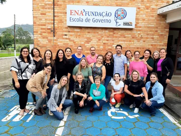 Vinte pessoas posam para foto em ambiente externo, ao fundo letreiro Fundação ENA