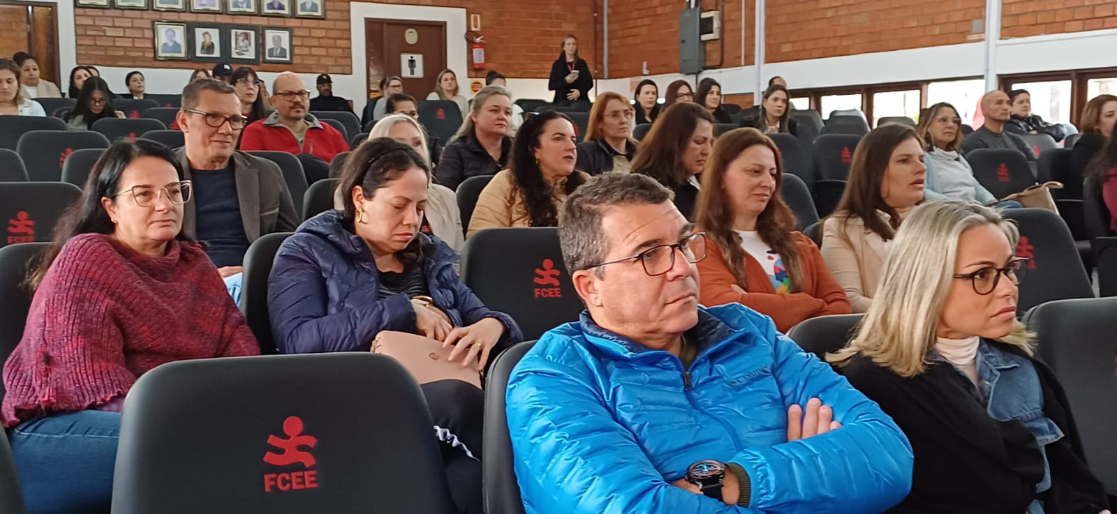 vinte pessoas sentadas em auditório olhando para frente