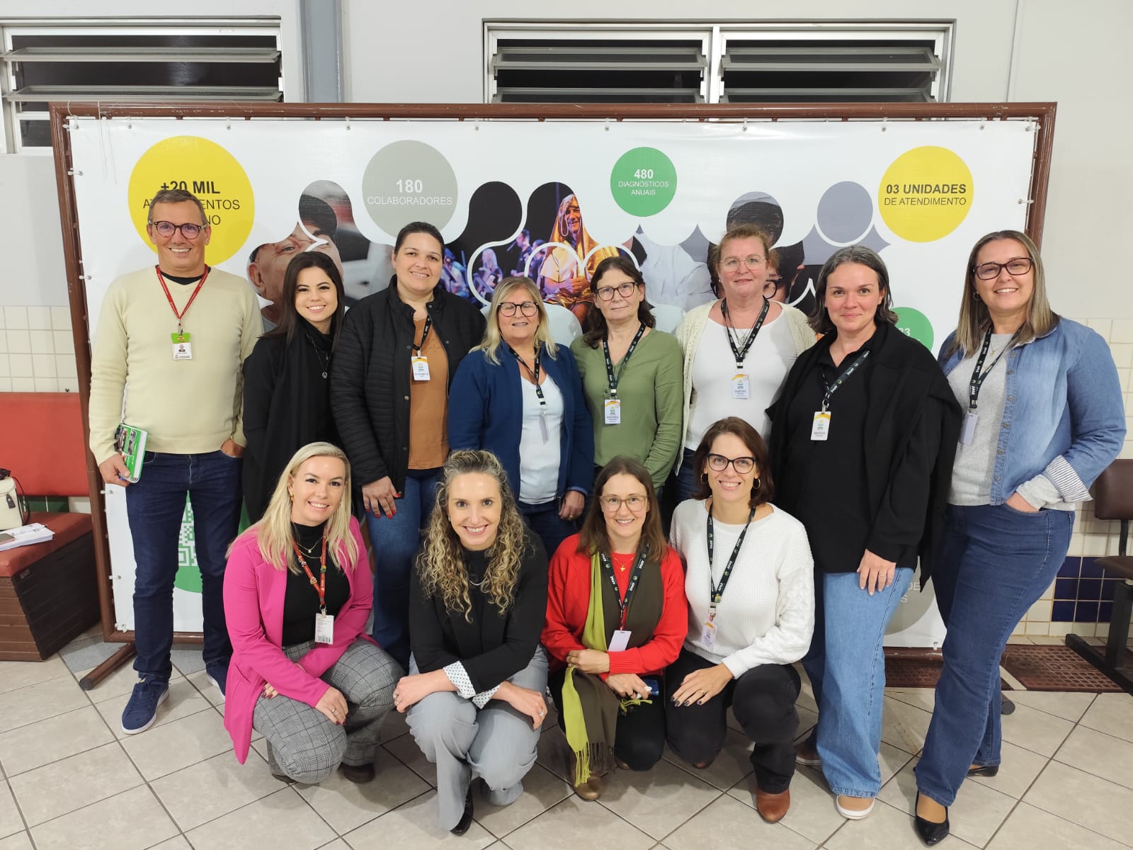 Vinte pessoas posam para foto em ambiente interno