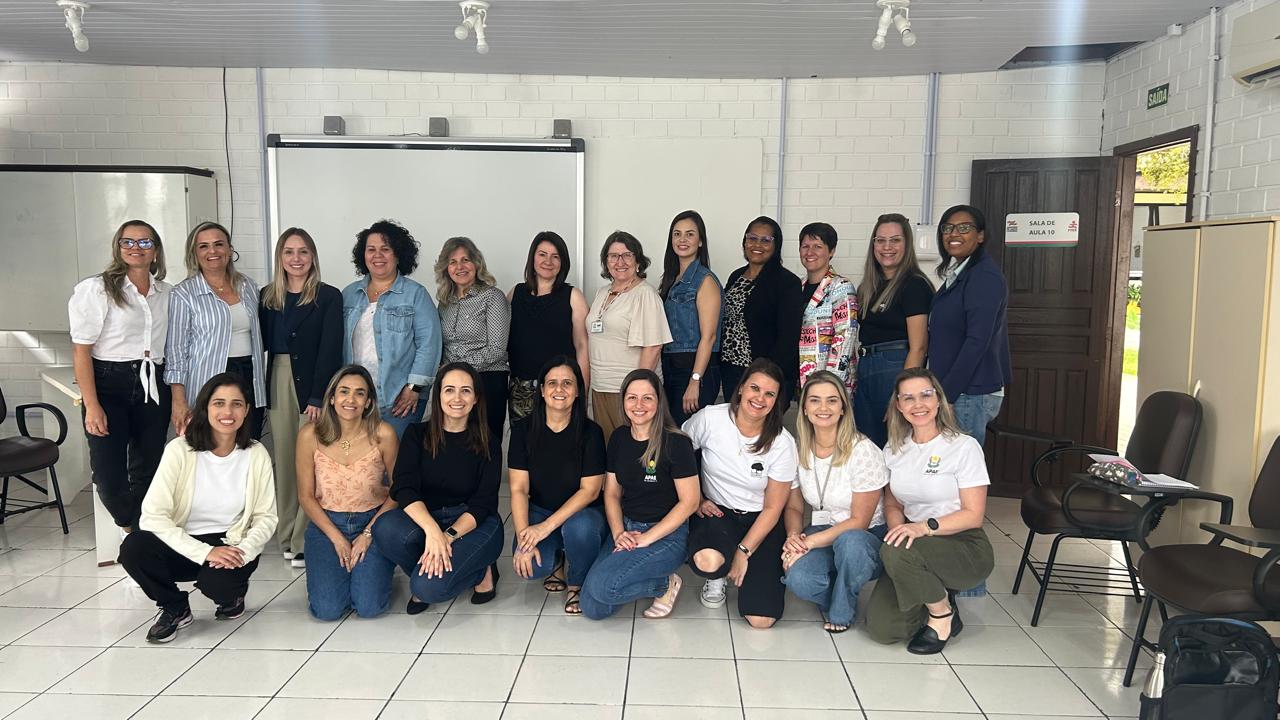 Vinte pessoas posam para foto em ambiente interno. 