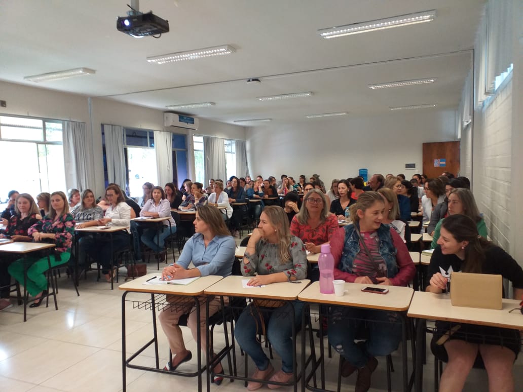 Participantes do curso sentados em sala de aula lotada