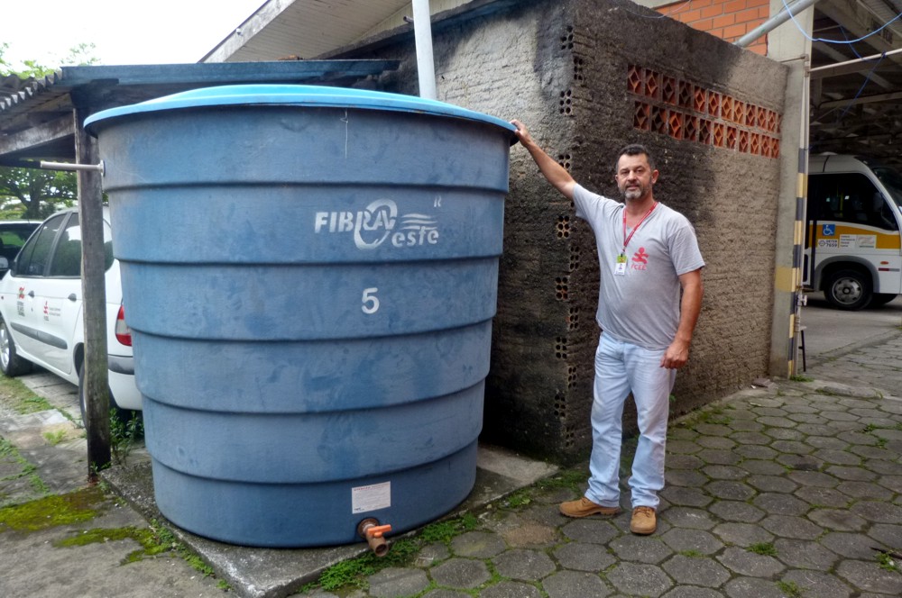 Motorista Murilo ao lado da caixa d´agua utilizada no sistema de captação de água da chuva