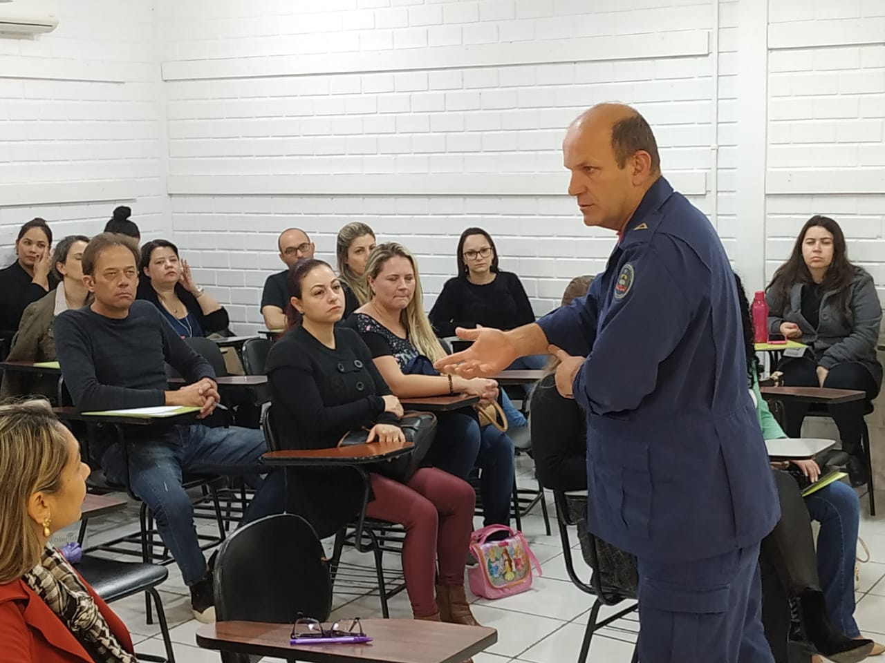 Bombeiro com uniforme fala diante de sala de aula lotada com profissionais da FCEE.