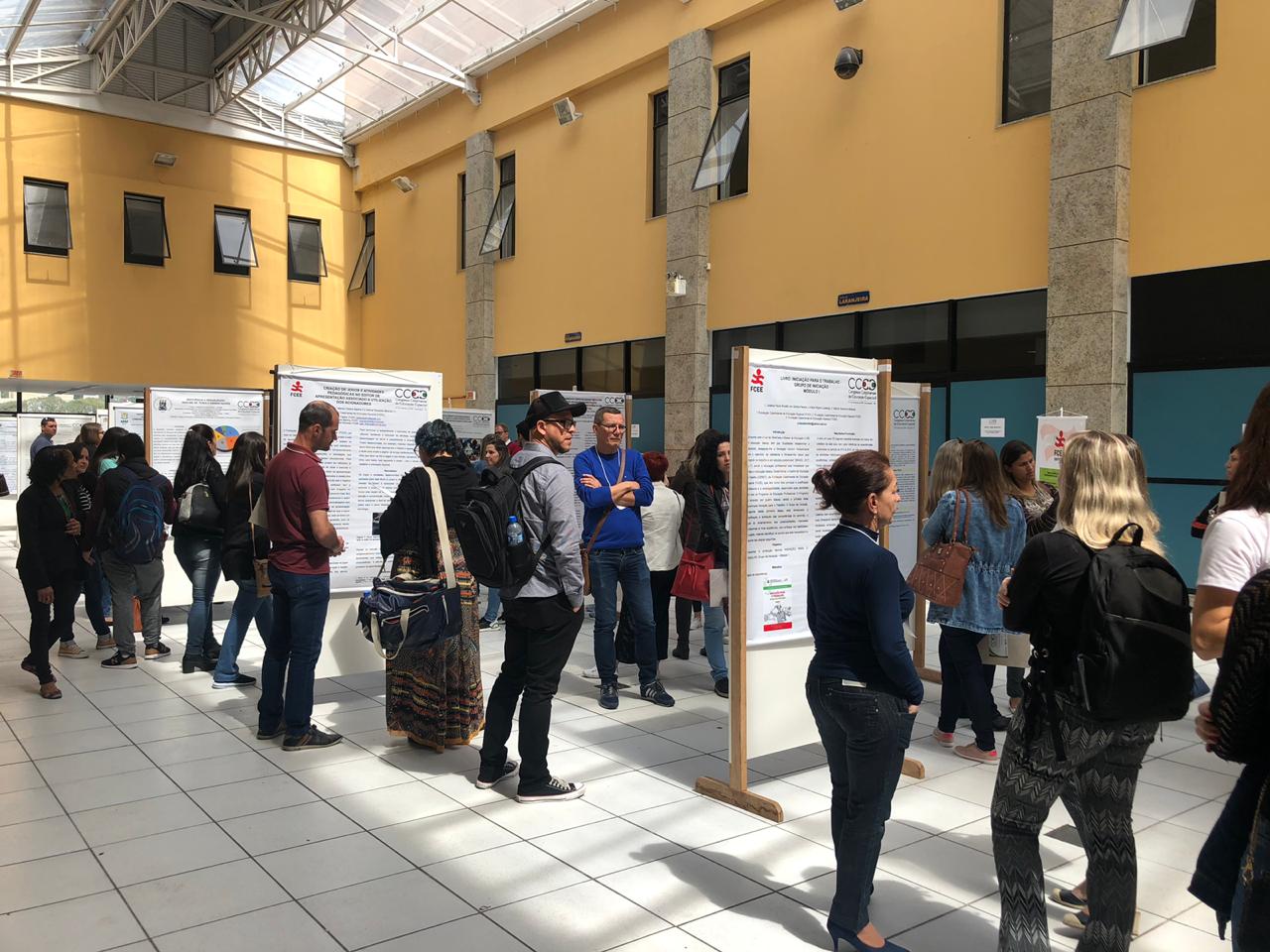 Exposição de pôsteres no Hall do Centro de Eventos da UFSC. Muitas pessoas em pé em volta dos pôsteres, alguns servidores da FCEE