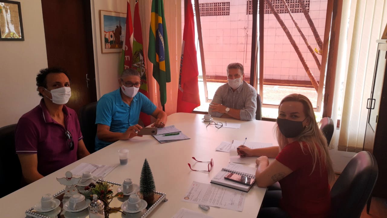 Quatro pessoas sentadas em mesa de reuniões.