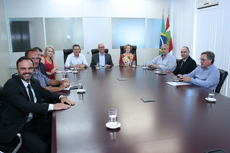 Na imagem, os participantes estão em reunião, sentados em volta de uma mesa. Entre os participantes estão o Secretário de Educação, Natalino Uggioni, o presidente da FCEE, Rubens Feijó, a Secretária de Estado do Desenvolvimento Social, Maria Elisa da Silveira De Caro, o Secretário Adjunto da Secretaria de Administração, Luiz Antônio Dacol, o Secretário Adjunto da Secretaria da Saúde, André Motta Ribeiro, e o Assessor do Secretário de Estado da Fazenda , Atair Derner Filho. 