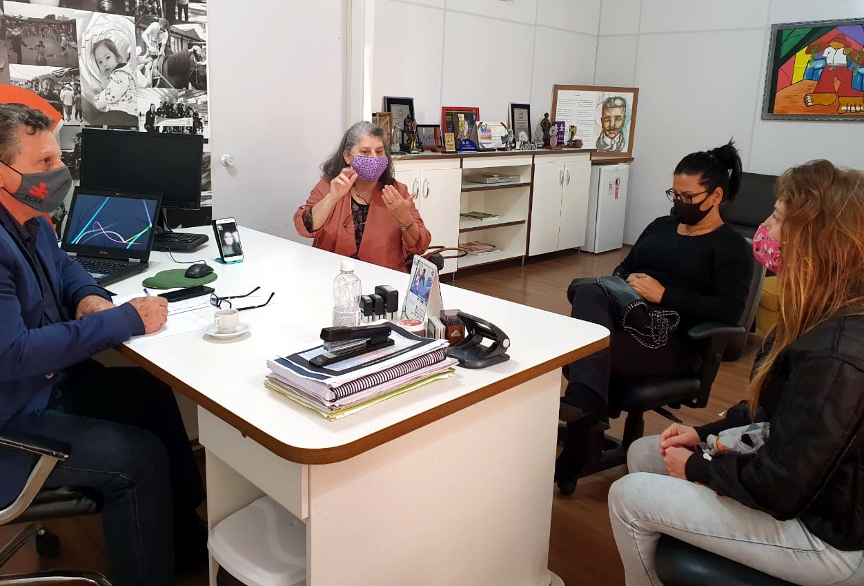 Quatro pessoas reunidas em volta de uma mesa no Gabinete do Presidente da FCEE, todos usam máscaras e uma delas gesticula com as mãos. 