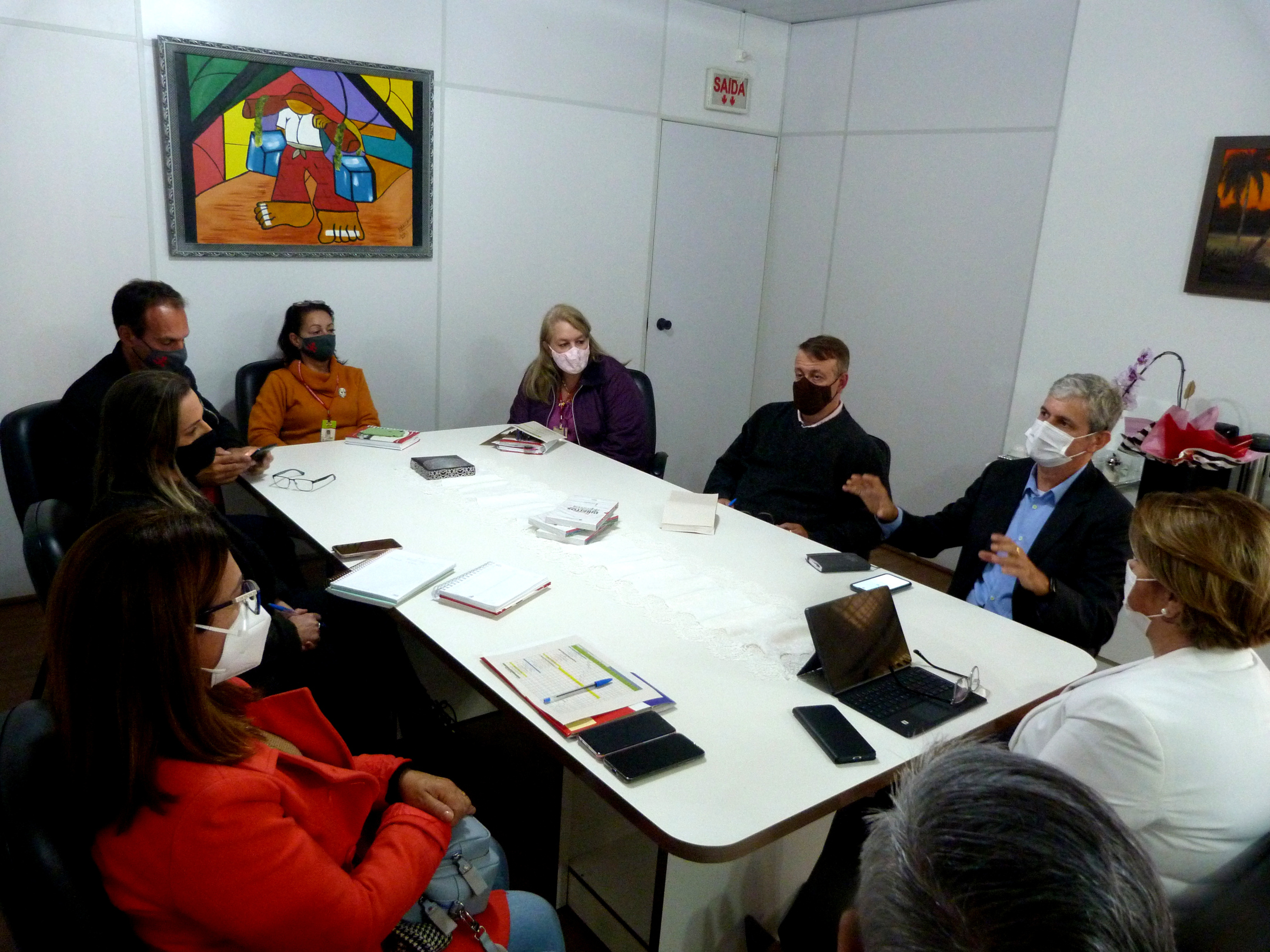 Nove pessoas sentadas, sala de reuniao