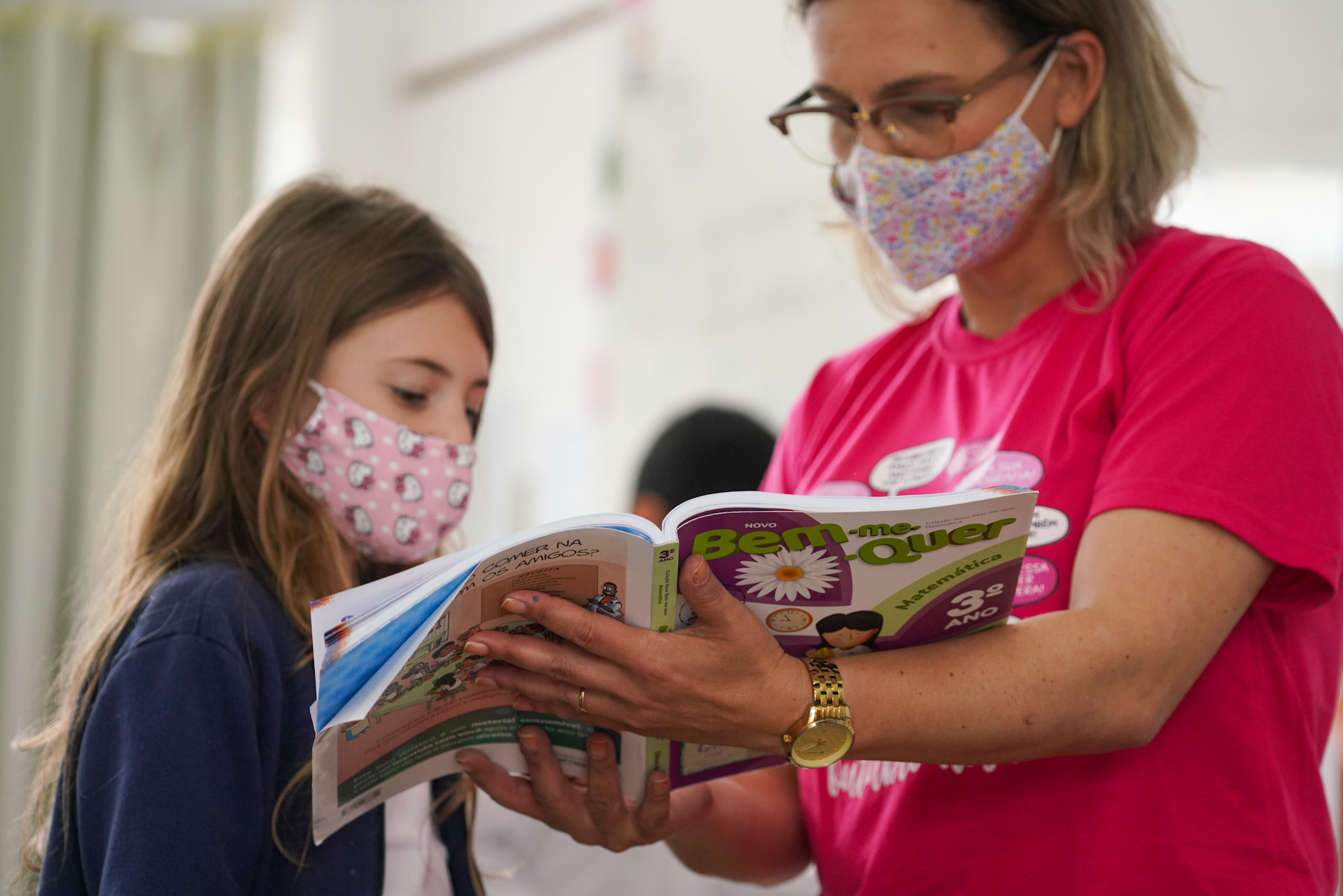 Ambiente interno. Mulher segurando um livro para uma criança ver.