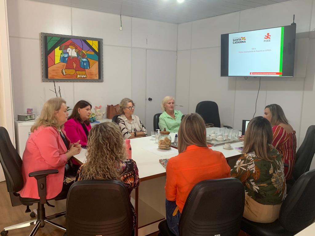 dez pessoas sentadas em mesa de reunião, ambiente interno