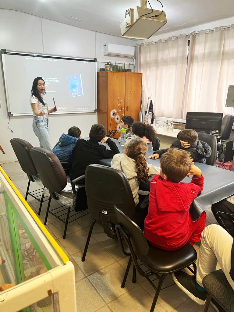 Foto de sala de aula, crianças sentadas olhando para professora em pé