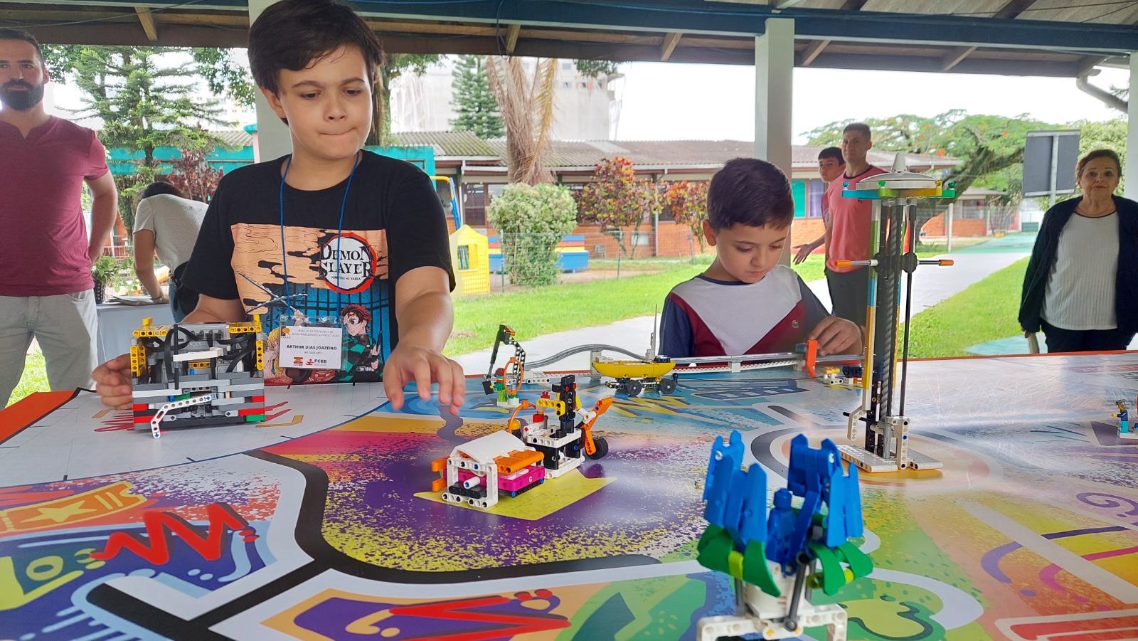 A imagem mostra um garoto manuseando sobre uma mesa pequenos brinquedos robóticos