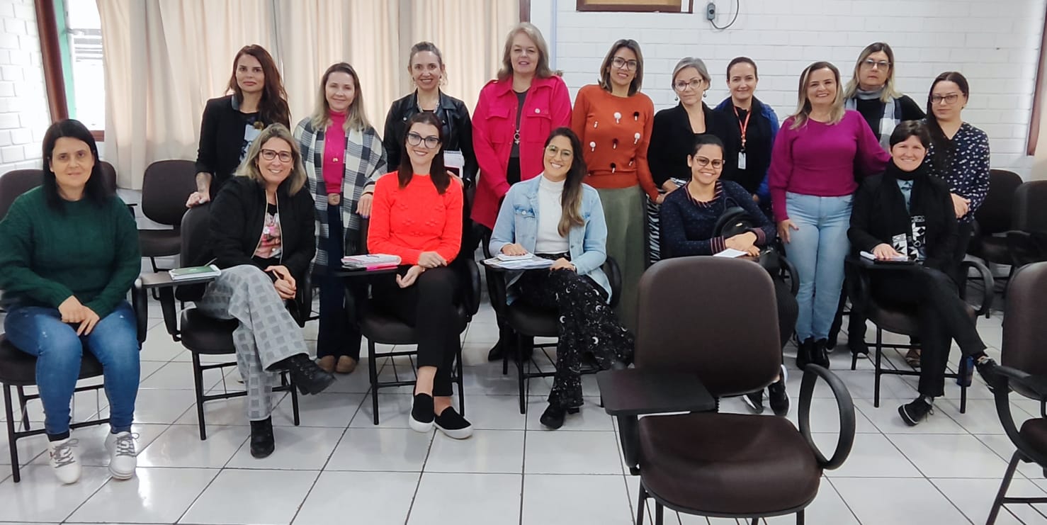 ambiente interno, sala de aula, 15 pessoas sentadas posam para foto