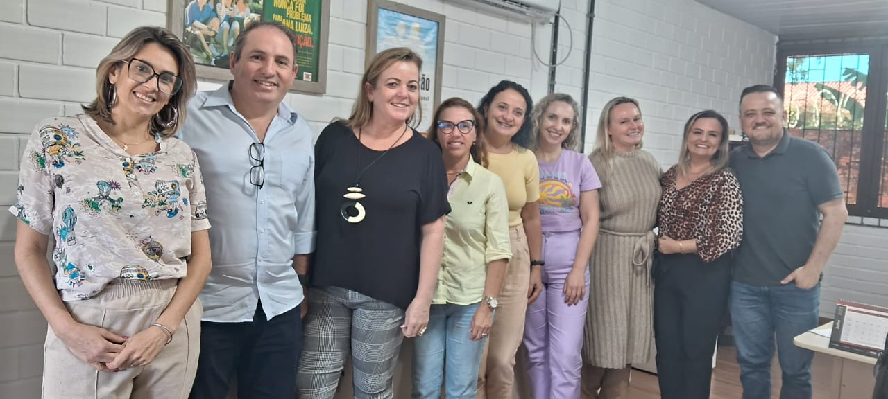 Oito pessoas em pé posam para foto, ambiente interno